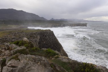 Asturias kıyıları Bufones de Pria 'da bulutlu bir günde dalgalar ve dalgalar kayalık kıyılara vuruyor.