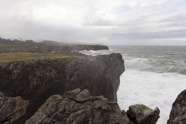 Asturias 'ta Bufones de Pria' nın manzarası bulutlu bir günde dalgalı denizler ve kıyılarda dalga spreyi