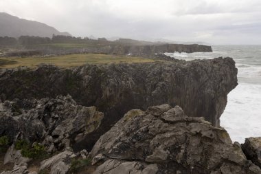 Asturias 'ta Bufones de Pria' nın manzarası bulutlu bir günde dalgalı denizler ve kıyılarda dalga spreyi