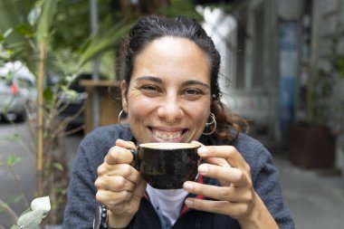 Genç İspanyol kadının portresi. Dışarıda tek başına kahve içiyor. Gülümsüyor. 