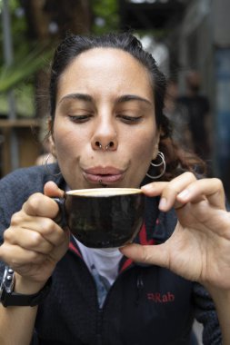 Genç İspanyol kadının portresi. Dışarıda tek başına kahve içiyor. Gülümsüyor. 