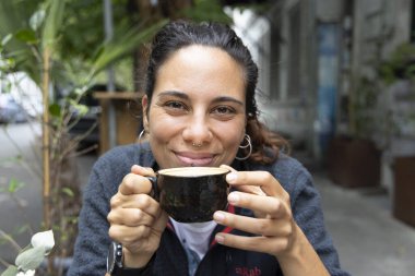 Genç İspanyol kadının portresi. Dışarıda tek başına kahve içiyor. Gülümsüyor. 