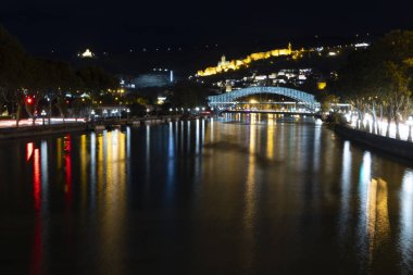 Tiflis şehir merkezinin panoramik manzarası. Geceleri kilise ve nehir üzerinde barış köprüsü. 
