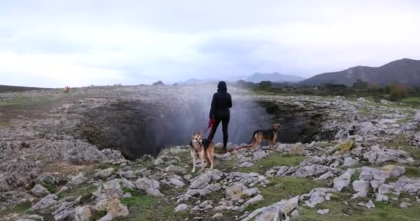 在一个阴天 在西班牙大西洋海岸的Bufones Pria Blowhole 一个带着两只狗的年轻女人 — 图库视频影像