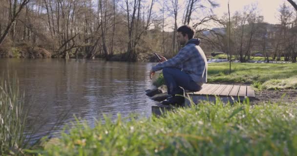 Sorglig Ung Man Håller Smarttelefon Pir Bredvid Floden Morgonen Med — Stockvideo