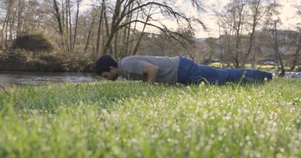 Человек Делает Отжимания Реки Траве Яркий Солнечный День — стоковое видео