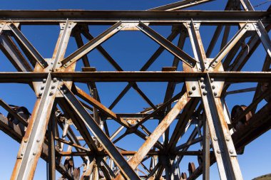 Paslı, güneşli bir günde paslı çelik kirişlerin oluşturduğu endüstriyel metal yapı..