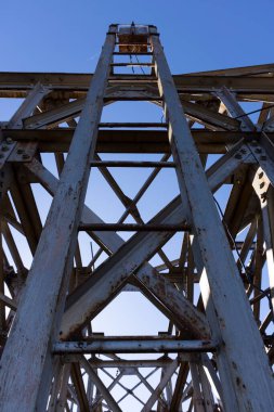 Paslı, güneşli bir günde paslı çelik kirişlerin oluşturduğu endüstriyel metal yapı..