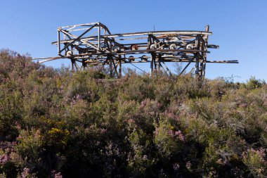 Asturias 'ın Tormaleo bölgesinde ilkbahar güneşli bir günde kömür madeni kablo arabasından beton baz alan metal yapı kulesi terk edilmiş sanayi kablosu
