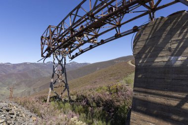 Asturias 'ın Tormaleo bölgesinde ilkbahar güneşli bir günde kömür madeni kablo arabasından beton baz alan metal yapı kulesi terk edilmiş sanayi kablosu