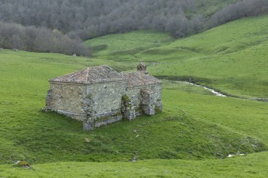İspanya 'daki Ponga doğal parkında güneş doğarken yeşil çayırdaki şapel..