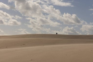 İnsanlar açık güneşli bir çölde kumullarda yürüyorlar mavi gökyüzüyle.