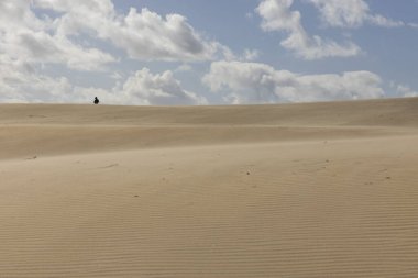 İnsanlar açık güneşli bir çölde kumullarda yürüyorlar mavi gökyüzüyle.
