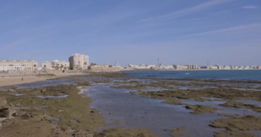 Güneşli bir günde açık gökyüzü tavasıyla mavi okyanusun yanına yüzler ve okyanus inşa ederek Cadiz şehri cepheleri inşa ediyor.