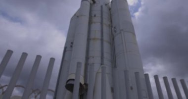 Beyaz uzay gemisi yerdeki roketi koyu yağmur bulutlarıyla yukarı doğru eğiyor.