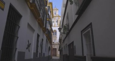 Güneşli bir günde Sevilla 'daki Iglesia de Santa Cruz kilisesi dar sokaktan mavi gökyüzü izleme görüntüleriyle