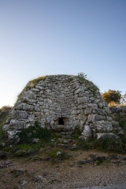 Doğada yuva yapmış antik bir taş yapıya bir başka bakış açısı, tarihin ve çevreleyen doğal güzelliğin karışımını tasvir ederek, sakin bir atmosfer yaratıyor..