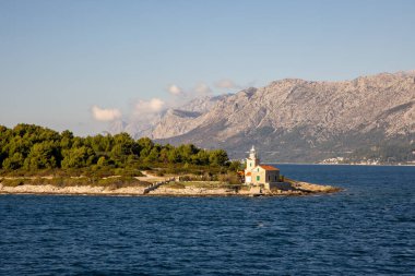 Huzurlu sular ve görkemli dağlarla çevrili küçük bir adada güzel bir deniz feneri. Doğanın kucağında huzur ve macera hissi uyandırmak için mükemmel..