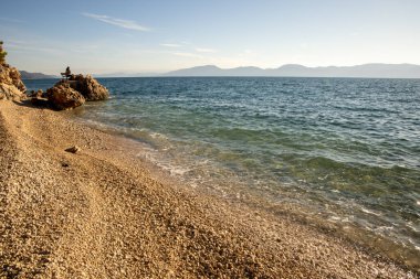 Kibar dalgaların çakıllı bir sahile vuruşunun resimsel bir sahnesi. 