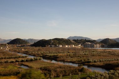 Bu resim güzel bir bataklık manzarasını sarmal su yollarıyla tasvir ediyor, sakin bir doğal ortamda karayla su arasındaki uyumu gösteriyor..