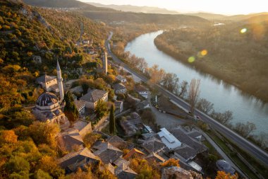 Kıvrımlı bir nehrin nefes kesici hava manzarası canlı sonbahar renkleriyle kucaklanmış, doğaya uyum içinde yerleşmiş geleneksel mimariyi gözler önüne seriyor..