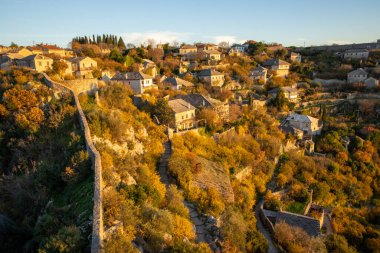 This breathtaking view captures a rustic village surrounded by colorful autumnal foliage, illustrating a perfect blend of nature's beauty and human architecture. clipart