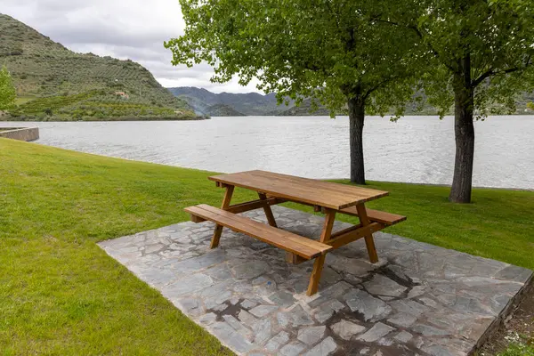 Huzurlu bir nehir kenarına kurulmuş ahşap banklı davetkar bir piknik alanı, doğanın sükuneti ve rahatlığı arasında dinlenme sunuyor..