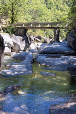 Görüntü çok sayıda çivit boyalı tekstil çantasının rastgele istiflenmiş zemin kattaki yakın çekimini gösteriyor. Çantalar şekil ve boyut olarak düzensiz, sert ve desenli bir yüzey sergiliyorlar..  