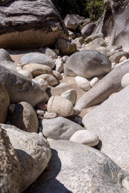 Yüksek çözünürlüklü yakın plan bir fotoğraf, çeşitli boylarda ve gri tonlarda nehir taşlarının bir derlemesini tasvir eder. Kayalar, görünür ışık ve gölge etkileşimi derinlik ve boyut yaratan pürüzsüz ve pürüzsüz dokular sergiler.. 
