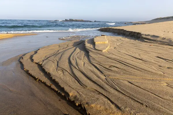 Yüksek açılı, kıyı kayaları oluşumuna yakın çekim. Görüntü, tortu tabakalarının kahverengi ve bronz tonlarında karmaşık desenlerini gösteriyor. Kayalar görünür erozyon sergiliyor..