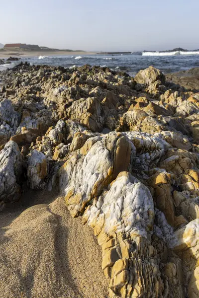 Kayalık bir yüzeye yakın çekim. Görüntü, ağırlıklı olarak bronz, kahverengi ve bej tonlarında, açık beyaz veya açık gri parçalı çeşitli boyutlardaki kayalardan oluşan bir koleksiyonu gösteriyor.. 