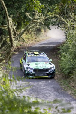 Ourense, İspanya, 13 Haziran 2025: Virajlı asfalt yolda keskin bir dönüş yapan ralli aracının orta açılı görüntüsü.