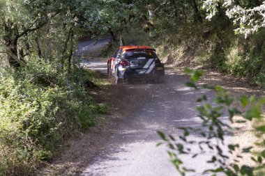 Ourense, İspanya, 13 Haziran 2025: Görüntü, yoğun bir ormanda dar ve asfaltsız bir yolda ilerleyen bir rali aracının arka görüntüsünü sergiliyor..
