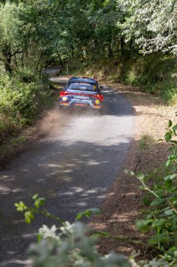Ourense, İspanya, 13 Haziran 2025: Görüntü tozlu toprak yolda hızla giden bir ralli aracının arka görüntüsünü gösteriyor. Araba hareket halinde, arkasında önemli bir toz bulutu oluşturuyor..
