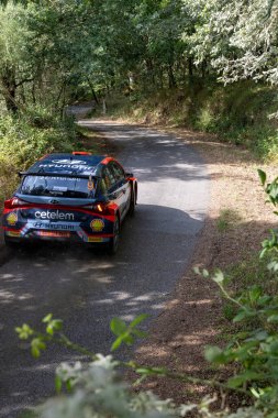 Ourense, İspanya, 13 Haziran 2025: Görüntüde yemyeşil bir orman boyunca asfalt bir yolda ilerleyen bir ralli aracının dikiz görüntüsü yer alıyor..