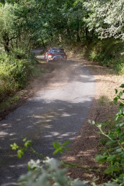 Ourense, İspanya, 13 Haziran 2025: Görüntü kırsal bir yolun yüksek açılı, uzak bir görüntüsünü sunuyor. Görünmeyen bir hareketin yarattığı bir toz bulutu..