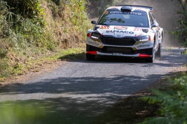 Ourense, İspanya, 13 Haziran 2025: Görüntü dar bir asfalt yolda keskin bir dönüş yapan beyaz ralli aracının yakın görüntüsünü sergiliyor.