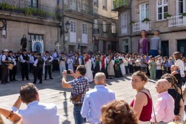 Allariz, İspanya, 13 Temmuz 2025: Büyük bir heykel taşıyan bir grup insan. İnsanlar siyah ve beyaz giyinmiş ve heykel çiçeklerle çevrili..
