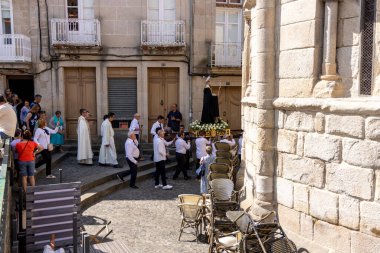 Allariz, İspanya, 13 Temmuz 2025: Büyük bir heykel taşıyan bir grup insan. İnsanlar siyah ve beyaz giyinmiş ve heykel çiçeklerle çevrili..