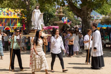 Allariz, İspanya, 13 Temmuz 2025: Bir grup insan bir geçit töreninde ellerinde bir heykel ile yürüyorlar. Sahne kutlama ve şenliktir.