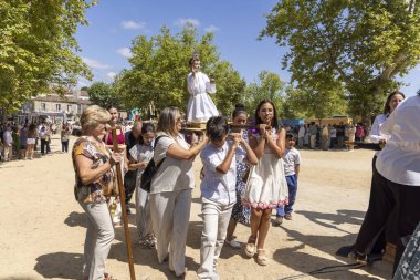 Allariz, İspanya, 13 Temmuz 2025: Bir grup insan dini bir heykel taşıyor. İnsanlar beyaz giyinmiş ve heykeli bir sopayla taşıyorlar. Sahne canlı ve şenlikli.
