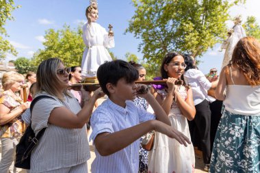 Allariz, İspanya, 13 Temmuz 2025: Bir grup insan dini bir heykel taşıyor. İnsanlar beyaz giyinmiş ve heykeli bir sopayla taşıyorlar. Sahne canlı ve şenlikli.