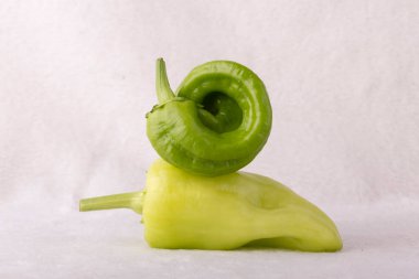 İki yeşil biber üst üste istiflenmiş. Biberler büyük ve spiral şeklinde. Tazelik ve bolluk kavramı, çünkü biberler sağlıklı ve besleyici bir besin seçeneği.