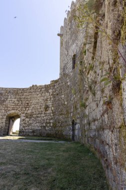 Ortasında küçük bir kemer olan taş bir duvar. Duvar yosunla kaplı ve kemer yolu açık.