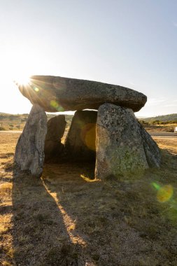 Ortasında küçük bir delik olan büyük bir kaya yapısı. Güneş kayaların üzerinde parlıyor, güzel ve huzurlu bir atmosfer yaratıyor.