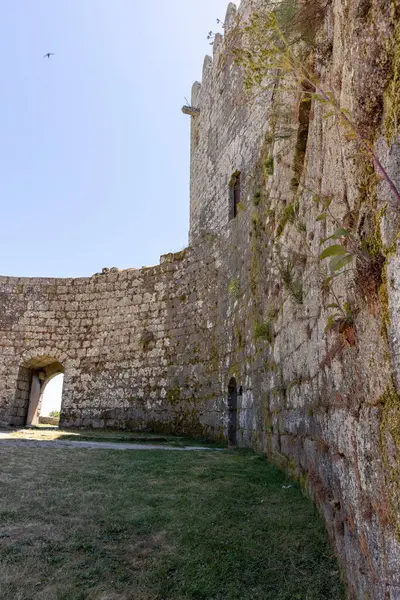 Ortasında küçük bir kemer olan taş bir duvar. Duvar yosunla kaplı ve kemer yolu açık.