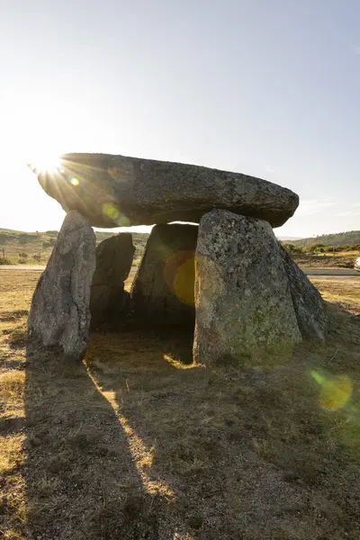 Ortasında küçük bir delik olan büyük bir kaya yapısı. Güneş kayaların üzerinde parlıyor, güzel ve huzurlu bir atmosfer yaratıyor.
