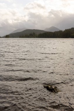 İçinde taş olan bir su kütlesi. Su sakin ve gökyüzü bulutlu.