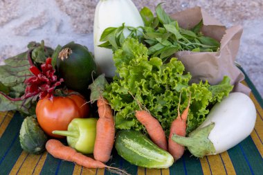 Masada havuç, salatalık ve domates de dahil olmak üzere çeşitli sebzeler sergilenmektedir. Sebzeler taze ve renkli, canlı ve sağlıklı bir atmosfer yaratıyorlar.