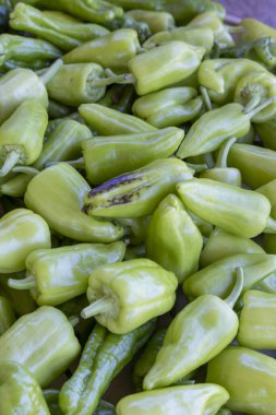 Bir demet yeşil biber üst üste yığılmış. Biberlerin hepsi farklı boyutlarda ve şekillerde.